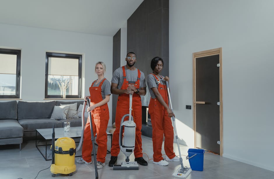 Three professional cleaning specialists from Kentish Town Carpet Cleaners are engaged in surface cleaning within a modern lounge area. The room features a light-colored tiled floor, which is being cle